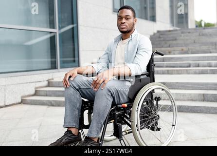 Portrait d'un malheureux homme noir malheureuse en fauteuil roulant à côté de siatrs sans rampe, se sentir stressé, espace libre Banque D'Images