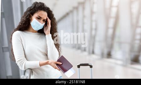 Annulation de vol. Contrarié jeune femme portant un masque médical attendant à l'aéroport Banque D'Images