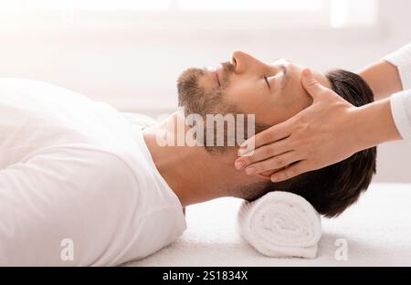 Femme thérapeute faisant un massage relaxant de la tête pour l'homme beau Banque D'Images