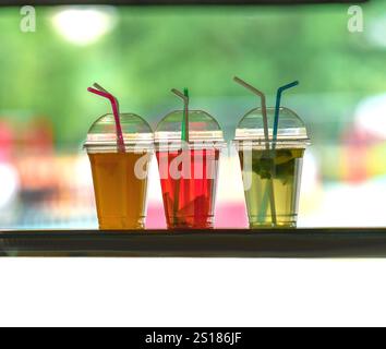 boisson gazeuse eau et jus dans des gobelets en plastique avec des pailles Banque D'Images