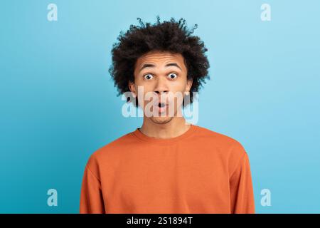 Jeune homme excité exprimant la surprise sur un fond bleu Banque D'Images