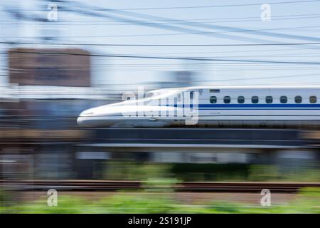 Le Japonais Nozomi Shinkansen quitte Nagoya. Le flou de mouvement souligne la vitesse du train et souligne son design aérodynamique élégant. Banque D'Images