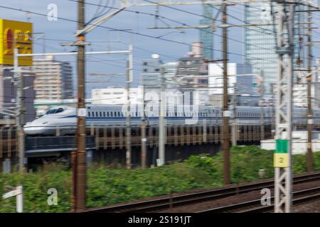 L'élégant train à grande vitesse Nozomi Shinkansen du Japon, qui se dirige vers Yokohama, est vu se diriger vers la ville de Nagoya en toile de fond. Banque D'Images