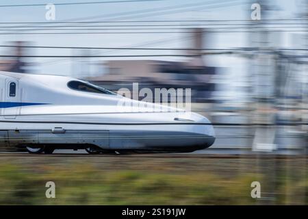 Le nez en bec de canard du Japonais Nozomi Shinkansen est capturé en tête floue. Le capuchon du conducteur du train est visible dans les vitres teintées. Banque D'Images
