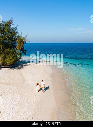 Couple se promène ensemble sur la plage de sable doux de l'île de Koh Munnork, entourée d'eaux cristallines. La végétation luxuriante encadre le paradis tranquille sous un ciel bleu vif en Thaïlande. Banque D'Images