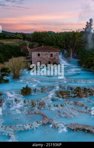 Les visiteurs apprécient les eaux thérapeutiques des thermes Saturnia en Toscane, Italie, comme le soleil se couche, illuminant la beauté naturelle et chaude, minérale- Banque D'Images