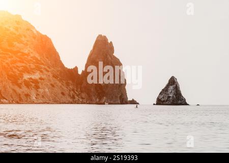 Falaises Sea kayak Crimea - Un paysage à couper le souffle de falaises escarpées s'élevant d'une mer calme, avec un kayak pagayant au premier plan. Banque D'Images