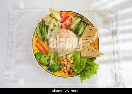 Bol de Bouddha avec salade, riz, tofu, pois chiches, brocoli, chou-fleur, tomates et pois verts, concombre et carotte Banque D'Images