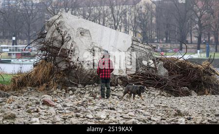 Dresde, Allemagne. 02 janvier 2025. Un homme se tient sur les rives de l'Elbe sur le site de démolition du côté de Neustadt devant un morceau de gravats du pont Carola partiellement effondré. Crédit : Robert Michael/dpa/Alamy Live News Banque D'Images