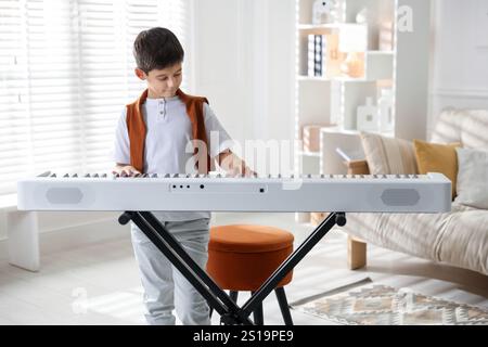 Garçon mignon jouant synthétiseur à la maison. Instrument de musique électronique Banque D'Images