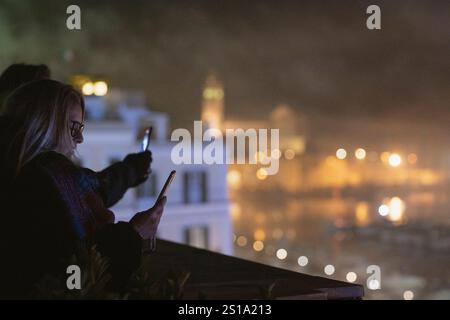 Trani, Italie. 1er janvier 2025. Les gens enregistrent le concert en utilisant leur téléphone portable depuis une terrasse alors que le chanteur Tony Hadley se produit avec son groupe, Spandau Ballet pour le concert de la Saint-Sylvestre dans la ville côtière de Trani. (Photo de Valeria Ferraro/SOPA images/SIPA USA) crédit : SIPA USA/Alamy Live News Banque D'Images