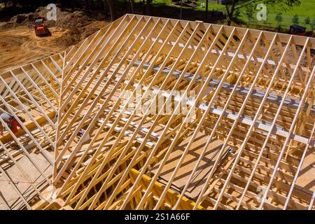 Les travailleurs sont occupés à assembler des poutres de toit en bois sur le chantier de construction, créant le cadre du nouveau bâtiment. Banque D'Images