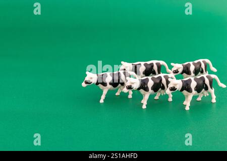 Groupe de figurines de vache en plastique noir et blanc sur fond vert Banque D'Images