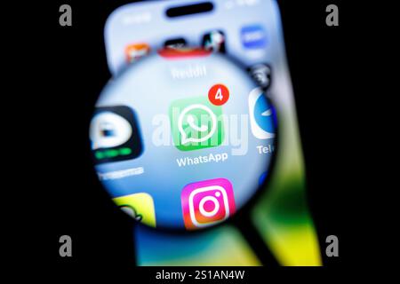 29 décembre 2024, basse-Saxe, Norden : le logo de l'application Whatsapp peut être vu à travers une loupe sur l'écran d'un smartphone sur 29.12.2024.WhatsApp est un service de messagerie instantanée fondé en 2009 qui fait partie de Meta Platforms depuis 2014. Les utilisateurs peuvent échanger des messages texte, des images, des fichiers vidéo et audio ainsi que des informations de localisation, des documents et des coordonnées entre deux personnes ou en groupes via WhatsApp. Photo : Matthias Balk/dpa Banque D'Images