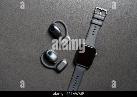 Casque sans fil non auriculaire et montre intelligente sur table en pierre grise, gros plan, vue de dessus Banque D'Images