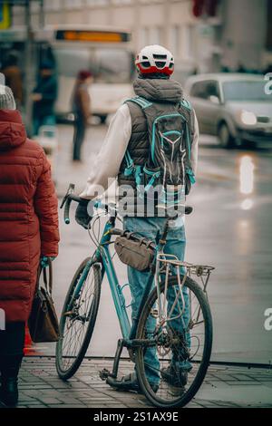 un homme avec un vélo et un sac à dos qui se prépare à traverser la route Banque D'Images