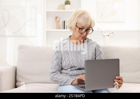 Belle femme âgée utilisant un ordinateur portable à la maison Banque D'Images