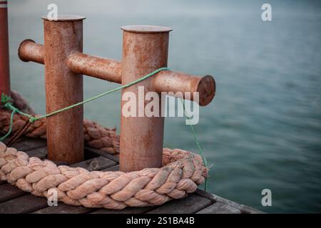 Bornes rouillées sur un quai avec des cordes épaisses et de la ficelle verte, gros plan de métal altéré, mettant en valeur l'équipement nautique et maritime dans un settin portuaire Banque D'Images