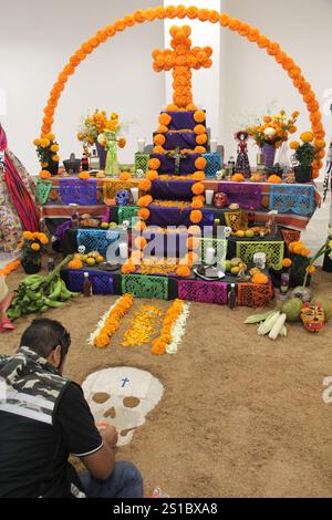 L'homme met à la main Day of the Dead offrande avec des crânes, des fleurs de cempasuchil et papel picado, tradition mexicaine Banque D'Images