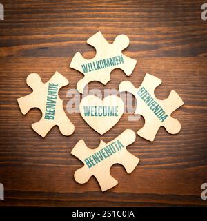 BIENVENUE. Anglais Italien Allemand Espagnol Français. Puzzle en bois en forme de coeur sur un fond de texture en bois. Banque D'Images