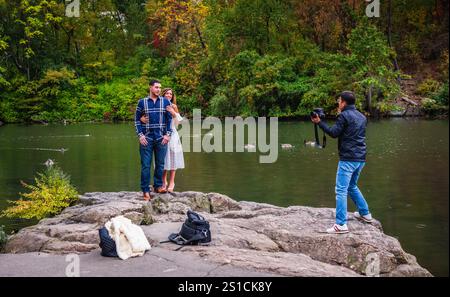 New York, NY États-Unis - 26 octobre 2017 : jeune couple photographié sur un rocher à Central Park avec un feuillage d'automne en arrière-plan à New York. Banque D'Images