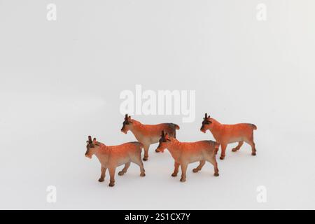 Quatre chèvres miniatures Toy en orange vif sur fond blanc Banque D'Images