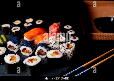 Plat sur fond noir. Nourriture japonaise sur plaque noire et fond noir. Différents types de sushi. Banque D'Images