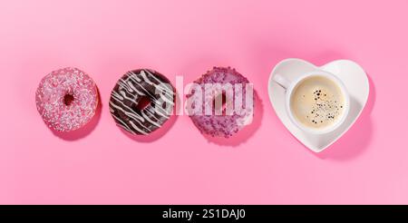 Un assortiment de beignets vibrants avec des garnitures colorées et une tasse à café sur une soucoupe en forme de coeur, disposés sur un fond rose dans un style plat, p Banque D'Images