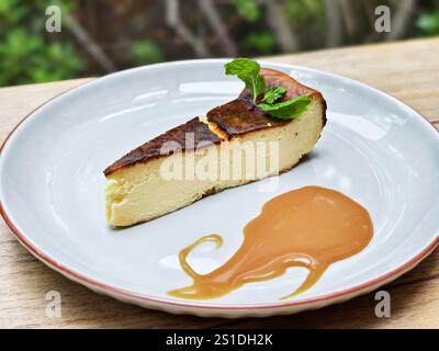 Une assiette de cheesecake basque brûlé avec sauce caramel et feuilles de menthe Banque D'Images