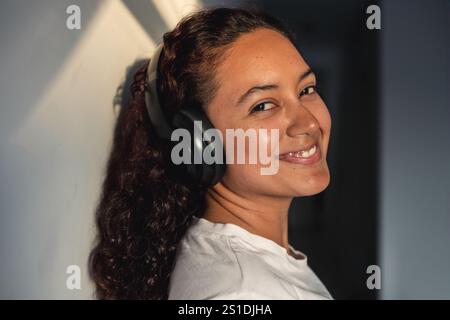 Jeune femme souriante confiante avec des écouteurs regardant la caméra Banque D'Images