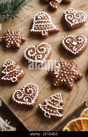 Biscuits de Noël en pain d'épice faits maison en forme de coeur et d'arbre décorés de glaçage blanc sur une table Banque D'Images