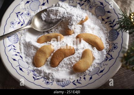 Enrobage de biscuits de Noël faits maison appelés Kipferl dans du sucre vanillé dans un bol Banque D'Images