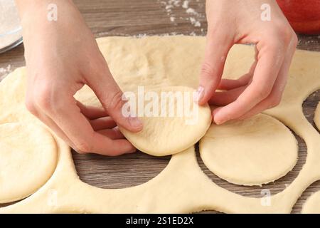 Femme faisant des pirozhki (tartes à pâtisserie farcies) à la table en bois, gros plan Banque D'Images