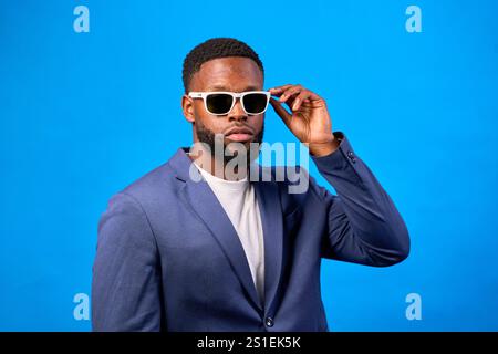 Homme d'affaires confiant ajustant les lunettes de soleil, mettant en valeur le style moderne et l'esprit d'entreprise sur fond dynamique Banque D'Images