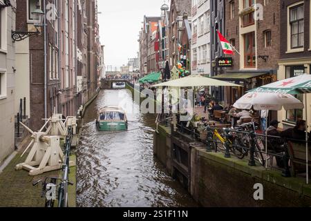 Un bateau longe les bars bordant le Oudezijds Voorburgwal dans le centre d'Amsterdam, aux pays-Bas. Banque D'Images