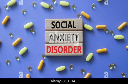 Symbole du trouble d'anxiété sociale. Mots conceptuels trouble d'anxiété sociale sur blocs de bois. Beau fond violet avec des pilules. Santé et social Banque D'Images