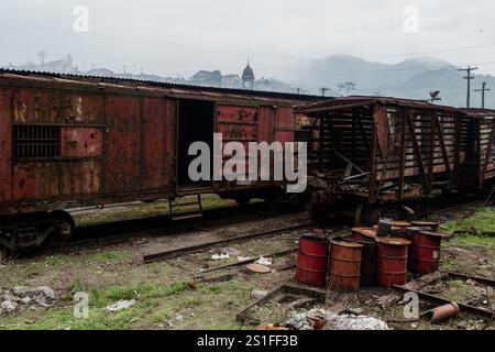 Santo Andre, SP, Brésil, 12 octobre 2013. Une vue d'un vieux wagon carrossé en acier rouillé avec les lettres RFFSA (Rede Ferroviaria Federal, Sociedade Anonima) 'Federal Railroad Network, S.A.', à côté d'un wagon carrossé en bois ruiné et de barils de pétrole abandonnés, au retrait de la cour de fer, dans la partie inférieure 'parte Baixa' du village ferroviaire de Paranapiacaba, localement connu sous le nom de 'Vila 'Vila Ferroviaria de Paranapiacaba', à Santo Andre, SP, Brésil. Banque D'Images