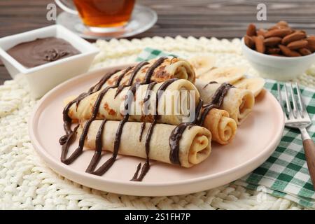 Délicieuses crêpes avec sauce chocolat et banane servies sur table, gros plan Banque D'Images
