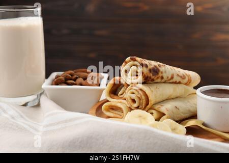 Délicieuses crêpes servies avec sauce chocolat et banane sur table, gros plan Banque D'Images