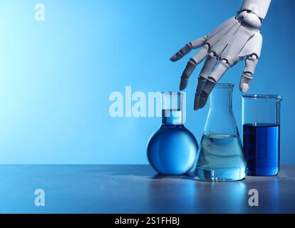 Intelligence artificielle. Main de robot et verrerie de laboratoire avec des liquides sur la table sur fond bleu clair, espace pour le texte Banque D'Images