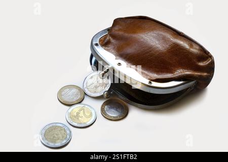 Porte-monnaie ancien légèrement ouvert en cuir marron. Cinq pièces en euros se trouvent devant le portefeuille. Découpe sur blanc. Format paysage. Légèrement op Banque D'Images