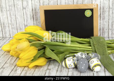 Tulipes jaunes avec des œufs de Pâques sur un fond texturé Banque D'Images