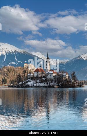 Photo verticale de belle vue sur la célèbre île de Bled au lac de Bled avec le château de Bled et les Alpes juliennes en arrière-plan en hiver, Slovénie Banque D'Images