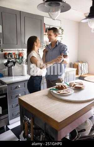 Heureux couple romantique jeune cuisinant et dansant à la maison Banque D'Images