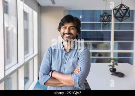 Heureux homme confiant directeur de société indienne debout dans le bureau Banque D'Images