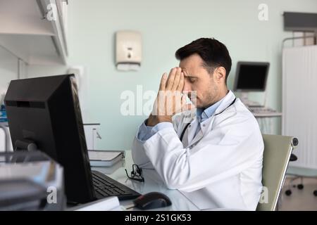 Malheureux docteur homme penché la tête sur les mains avec les yeux fermés Banque D'Images