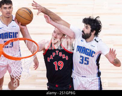 Toronto, Canada. 3 janvier 2025. Jakob Poeltl (C), des Raptors de Toronto, se lance dans un match de layup contre Goga Bitadze (R) d'Orlando Magic lors du match de saison régulière de la NBA 2024-2025 entre les Raptors de Toronto et Orlando Magic à Toronto, Canada, le 3 janvier 2025. Crédit : Zou Zheng/Xinhua/Alamy Live News Banque D'Images