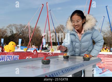 Pékin, Chine. 4 janvier 2025. Un visiteur essaie le curling de table au parc Yuanmingyuan à Pékin, capitale de la Chine, le 4 janvier 2025. Le festival de glace et de neige du parc Yuanmingyuan a débuté samedi. Crédit : Luo Xiaoguang/Xinhua/Alamy Live News Banque D'Images