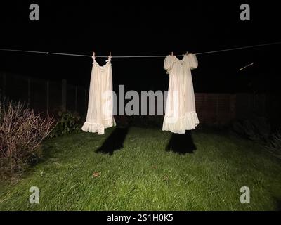 robe de chambre de nuit des années 1960 en tissu polyester nylon artificiel suspendu sur une ligne de lavage dans un jardin arrière à londres angleterre la nuit dans l'obscurité à l'air effrayant Banque D'Images