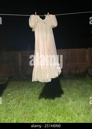 robe de chambre de nuit des années 1960 en tissu polyester nylon artificiel suspendu sur une ligne de lavage dans un jardin arrière à londres angleterre la nuit dans l'obscurité à l'air effrayant Banque D'Images